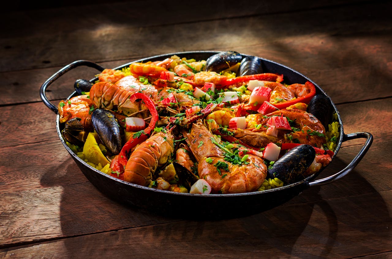 why-choose-us Tantalizing seafood paella with shrimp, mussels, and vegetables served in a traditional cast iron pan.